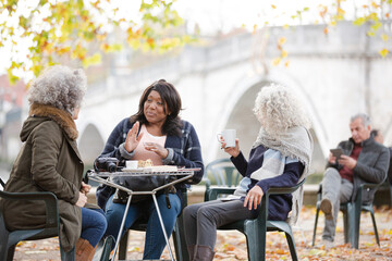 Portrait smiling, happy active senior women friends drinking coffee at autumn park cafe