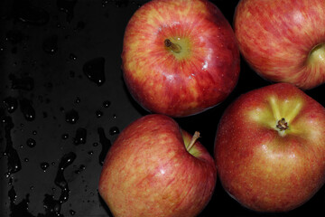 Large wet red apples with water drops on black background
