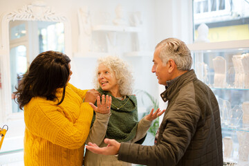 Sales assistant helping senior couple jewelry shopping