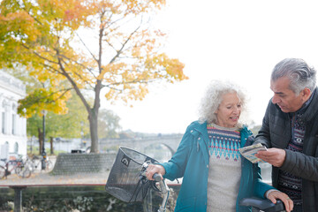 Adventurous senior couple with bicycles looking at map