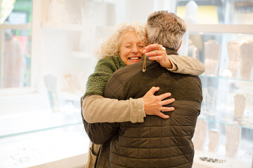 Happy senior woman hugging husband in jewelry store