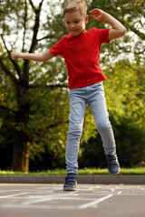 Cute little boy playing hopscotch outdoor. Street children's games. Selective focus.