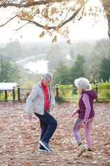 Fototapeta premium Affectionate active senior couple doing exercise at autumn park