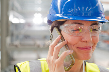 Close up female worker talking on smart phone in factory