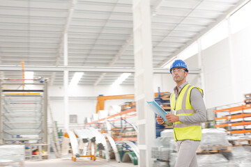 Male supervisor with paperwork walking in factory