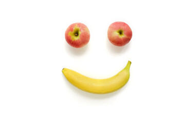 Happy fruits on a white background, big eyes made from ripe red apples, a mouth with a happy smile from a yellow banana, a cheerful face.