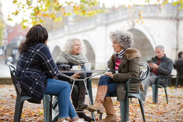 Portrait smiling, happy active senior women friends drinking coffee at autumn park cafe