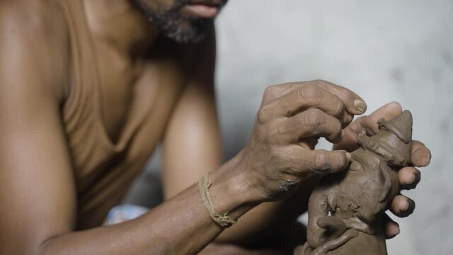 Close up of artist hands making clay ganesh idol for ganesha festival - concpet of religious festival preparations