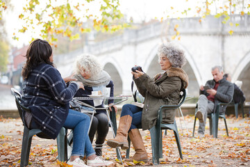 Portrait smiling, happy active senior women friends drinking coffee at autumn park cafe