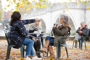 Portrait smiling, happy active senior women friends drinking coffee at autumn park cafe