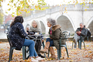 Portrait smiling, happy active senior women friends drinking coffee at autumn park cafe