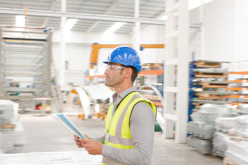 Male supervisor with paperwork walking in factory