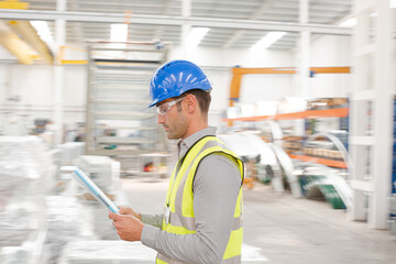 Male supervisor with paperwork walking in factory