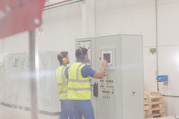 Engineers working at control panel in factory