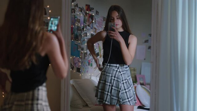 beautiful teenage girl taking selfie photo using smartphone posing in mirror sharing stylish fashion on social media enjoying weekend at home teen self image