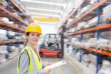 Portrait confident female supervisor with clipboard in warehouse