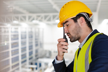 Male supervisor using walkie-talkie on platform in factory