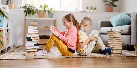 Two children sitting on the floor in the room and reading books
