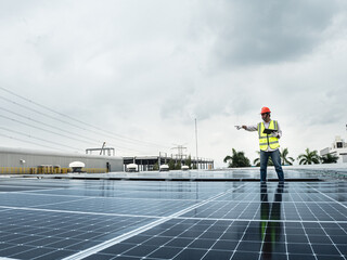  male engineer checks a photovoltaic (solar) plant and uses a recording tablet. mechanic in protective helmet. Man in uniform holding tablet.