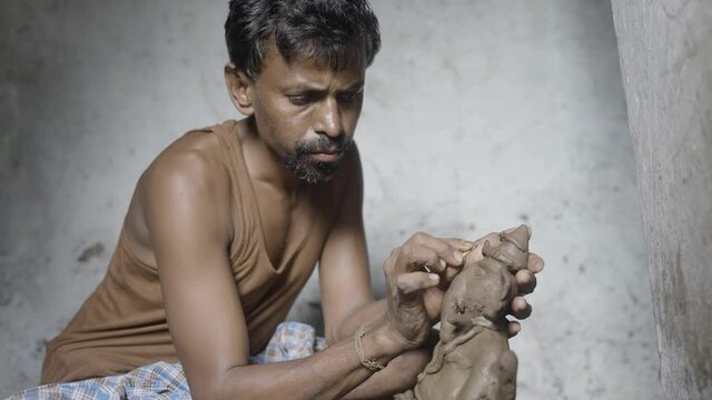 Concentrated artist making clay ganesh idol for ganesha festival - concpet of hindu religious festival preparations in India.
