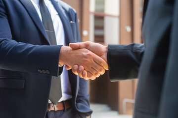 Handshake close-up. Businessman and his colleague are shaking hands in front of modern office...