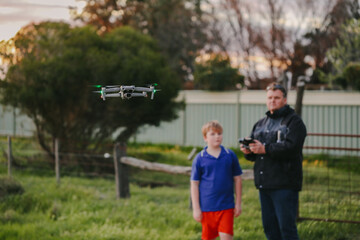 Father and son flying drone on country property