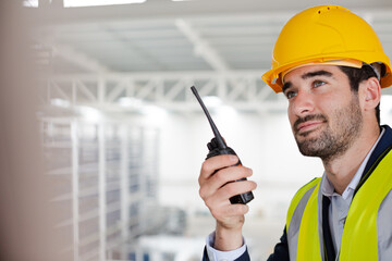 Male supervisor using walkie-talkie on platform in factory