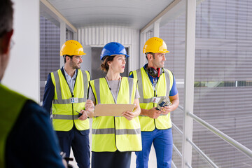 Supervisors and worker with clipboard in factory