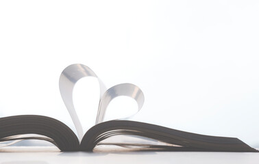 Soft light on surface of book pages in heart shape on white background