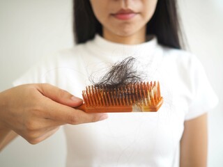 Woman looks at her hair falling from the comb. closeup photo, blurred.