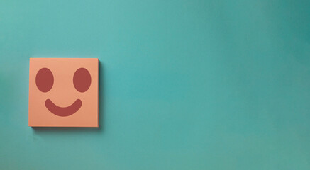 Happy face on pink notepage over light blue background with copyspace for put tex or logo.,positive thinking,positive attitude concept.