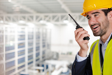 Male supervisor using walkie-talkie on platform in factory