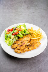 Homemade food concept. Chicken breast steak with black pepper served with salad and french fries in a white dish. Hight protein food.