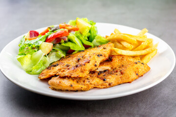 Homemade food concept. Chicken breast steak with black pepper served with salad and french fries in a white dish. Hight protein food.