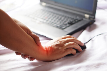 Woman holds her wrist pain from using  laptop computer's mouse. Concept :  suffering from carpal...