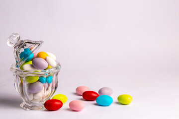Fototapeta na wymiar Colorful almond candies in the stylish,crystal candy bowl on white with copy space.The Sugar Feast concept. (Turkish name; Ramadan - Ramazan bayrami, Seker bayrami)