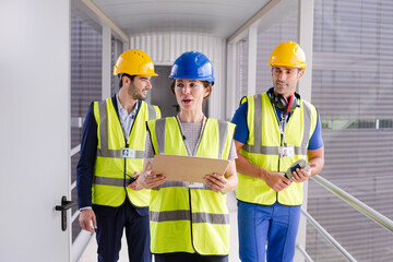 Supervisors and worker with clipboard in factory