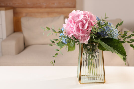 Beautiful hortensia flowers in vase on white table indoors. Space for text