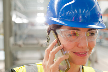 Close up female worker talking on smart phone in factory