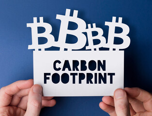 Hands holding a bitcoin cryptocurrency carbon footprint sign