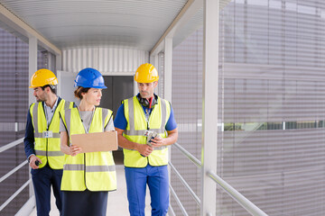 Supervisors and worker with clipboard talking in factory