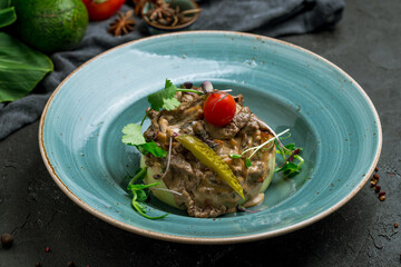 Stroganoff with mashed potatoes on blue plate on dark stone table