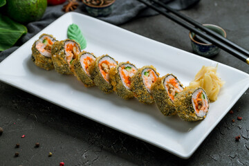 hot shrimp roll with eel on white plate on dark stone table