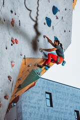 Young man professional rock climber practicing at training center in sunny day, outdoors. Concept of healthy lifestyle, tourism, nature, motion.