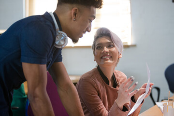 Two colleagues discussing paperwork in office