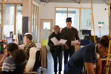 Two colleagues discussing paperwork in office