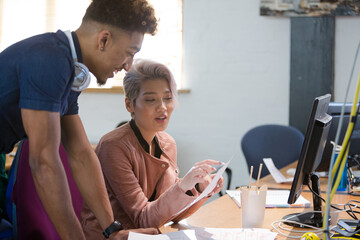 Two colleagues discussing paperwork in office