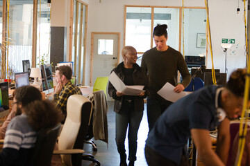 Two colleagues discussing paperwork in office