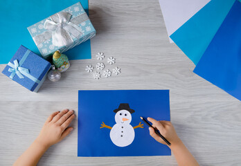 Children's hands make crafts. A snowman made of colored paper.Master class for children for...