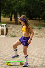 Stylish elementary school student learning to skateboard in city park. Young hipster little girl in...